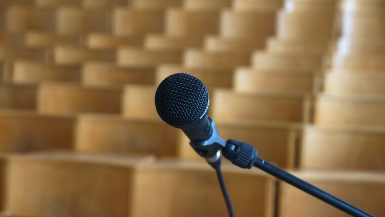 Blick vom Podium auf die Sitzreihen eines Hörsaals. Im Vordergrund ein Mikrofon.